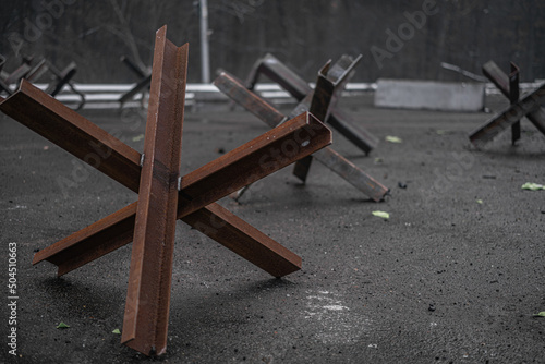 Steel anti-tank obstacles standing on asphalt road photo