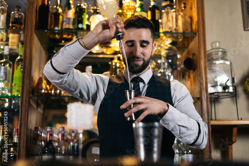 Professional young bartender preparing a cocktail photo