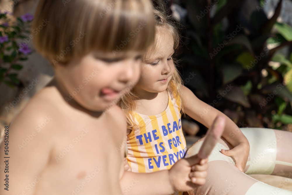 Children in swimsuits eating ice cream in pool outdoors