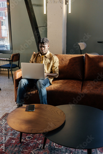 Black man browsing laptop during remote work photo