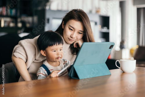 Asian little baby boy using ipad with his mom photo