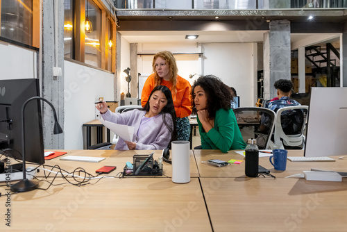 Diverse colleagues reading report at desk in office