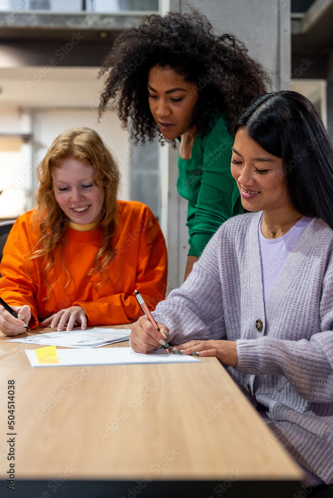 Diverse colleagues analyzing papers in office Diverse colleagues analyzing papers in office