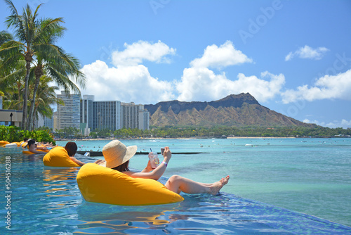 Bilde på lerret Tourists relaxing on rafts in oceanfront pool with Diamond Head and Pacific ocea