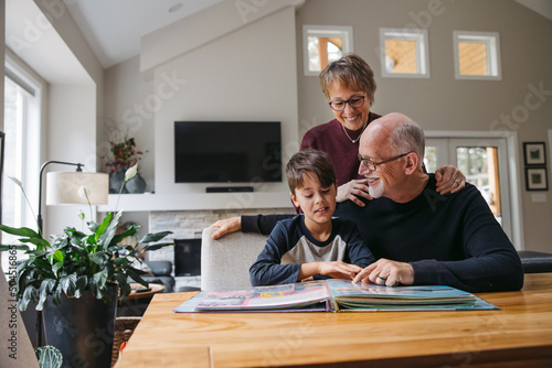 Grandparents and kid looking at photobook together. photo