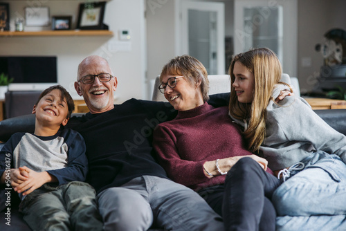 Grandparents and grandkids cudding on the couch.