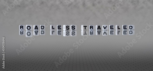 road less traveled word or concept represented by black and white letter cubes on a grey horizon background stretching to infinity