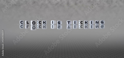 clock is ticking word or concept represented by black and white letter cubes on a grey horizon background stretching to infinity