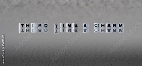 third time a charm word or concept represented by black and white letter cubes on a grey horizon background stretching to infinity photo