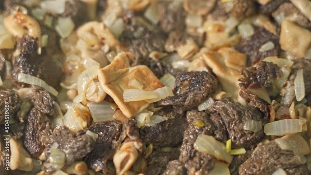 Morel mushrooms are fried in a frying pan, close-up Morel mushrooms are fried in a frying pan, close-up