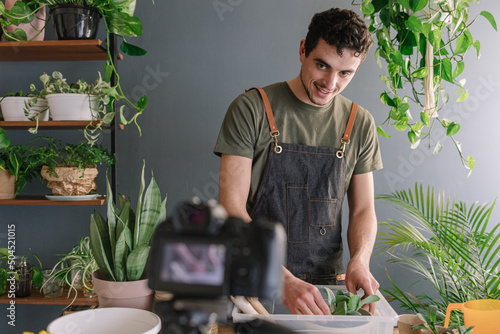 Smiling Man Repotting Pothos In Bigger Vase And Filming The Process photo