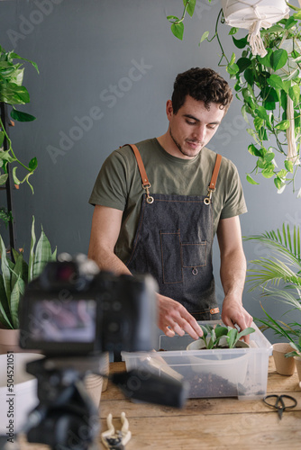 Man Repotting Pothos In Bigger Vase And Filming The Process photo