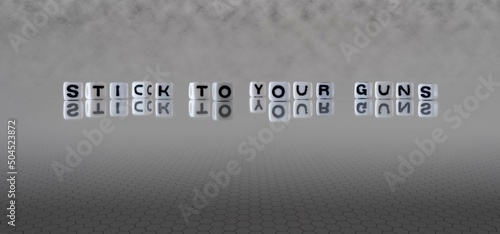 stick to your guns word or concept represented by black and white letter cubes on a grey horizon background stretching to infinity photo