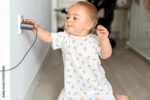Cute baby trying to pull out charger from socket