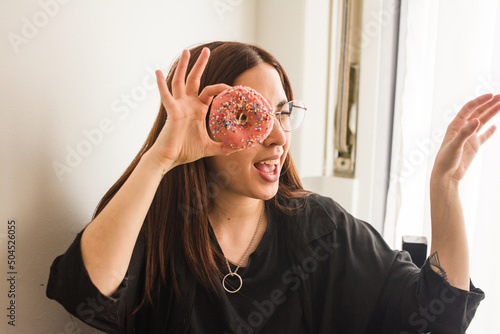 Latina woman looking through a donut hole jokingly photo