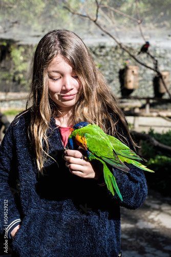 beautiful young girl giving nectar to Rainbow Lorikeet photo