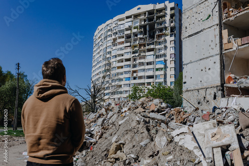 Chernihiv Ukraine 2022: a guy looks at the ruins after an air strike. Rear view. The building was destroyed after the air strike. Ruins during Russia's war against Ukraine.
