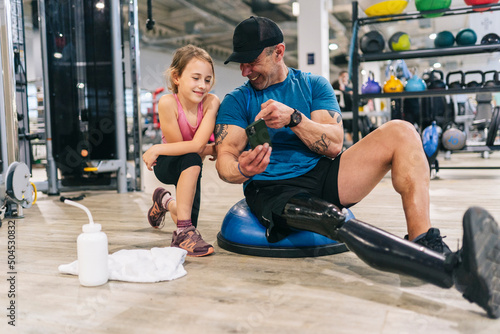Athletic man with leg prosthesis and girl in gym