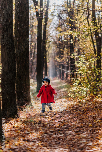 Little girl in a red coat walk in autumn forest