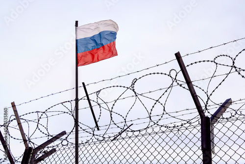 Fotografie View of russian flag behind barbed wire against cloudy sky