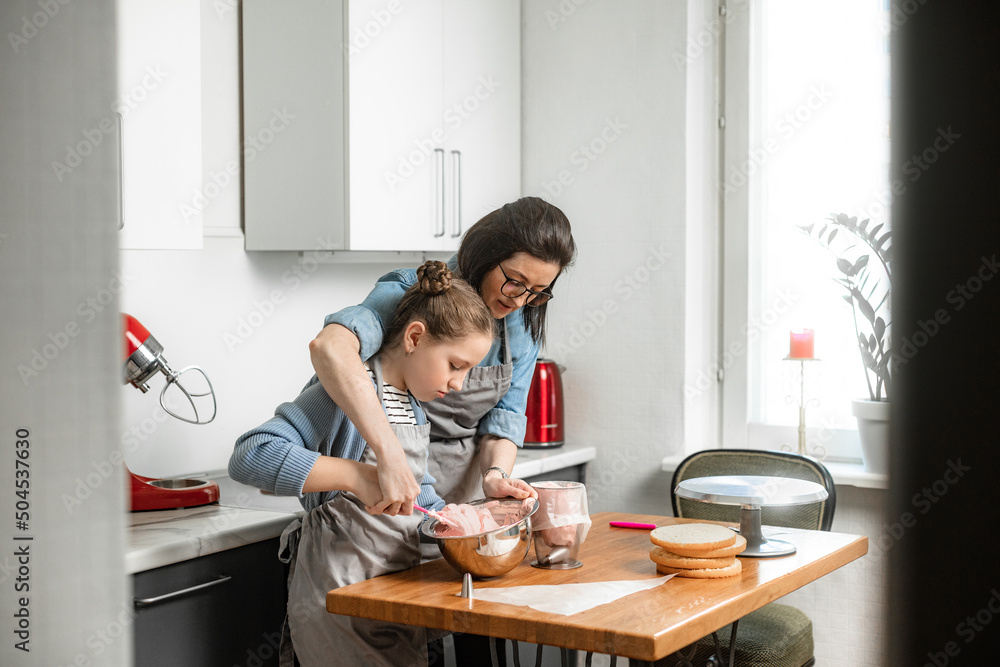 The family enthusiastically prepares a cake in the kitchen The family enthusiastically prepares a cake in the kitchen