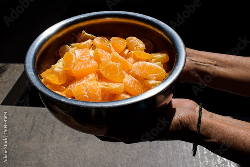 Slices of orange peeled completely and chopped and cut to make orange juice or orange fruit salad. Cut malta, mosambi, santra in container photo