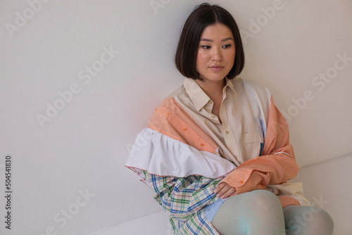 Brunette model sitting on floor in patchwork clothes photo