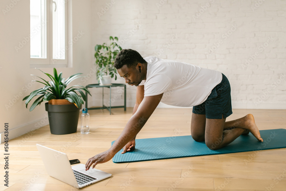 Man playing online workout class on laptop Man playing online workout class on laptop
