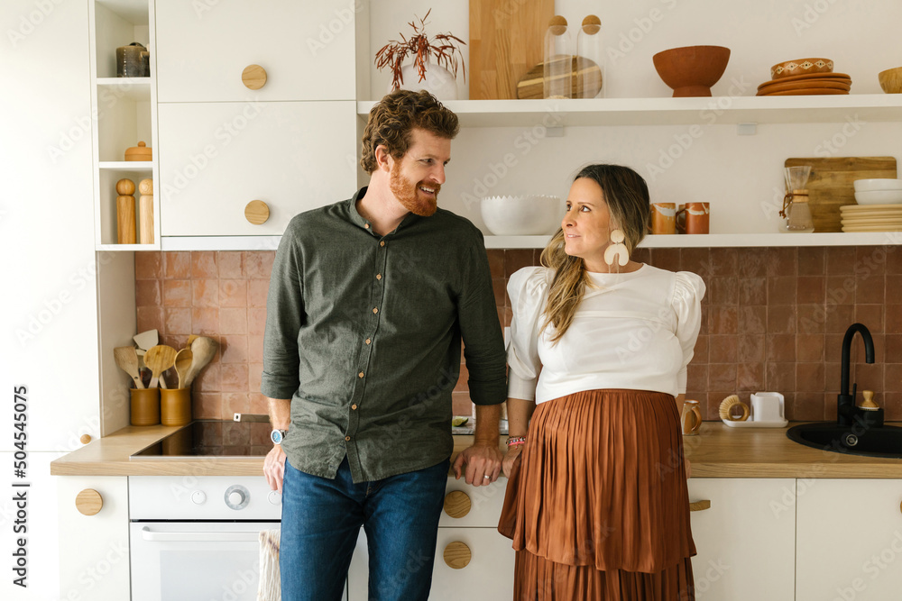 Happy couple looking at each other in the kitchen Happy couple looking at each other in the kitchen