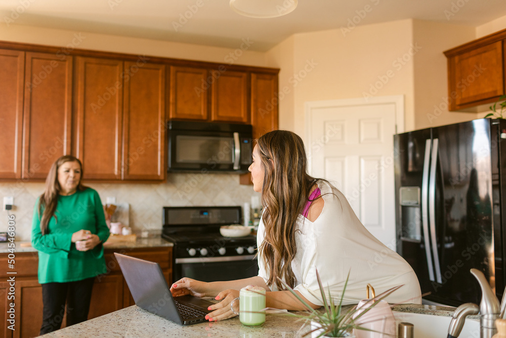 Mother and daughter with laptop talking in kitchen Mother and daughter with laptop talking in kitchen