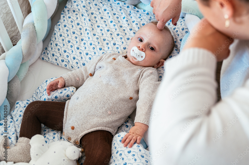 Crop mother putting baby for sleeping in cot Stock Photo Adobe Stock