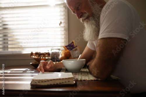 Man reading the bible at kitchen table. photo