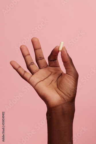 Dark skinned hand holding a pill
