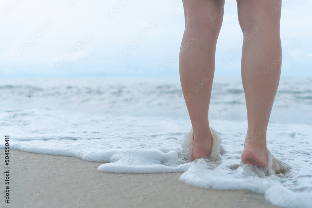 On a sand tropical beach with a blue sky background, a woman's feet walk slowly and relax. On a sand tropical beach with a blue sky background, a woman's feet walk slowly and relax.