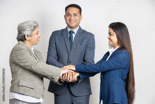 Fototapeta Naklejka Na Ścianę i Meble -  Group of positive indian business partners putting their hands together isolated on white studio background. Asian corporate people teamwork and unity.