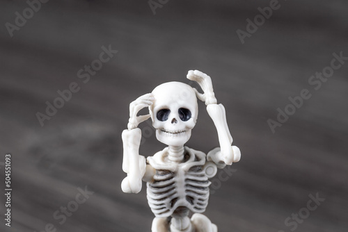 Fototapeta Naklejka Na Ścianę i Meble -  Skeleton figurine holding his head. Worried and frustrated toy, headache, tired, disappointed, shocking concept