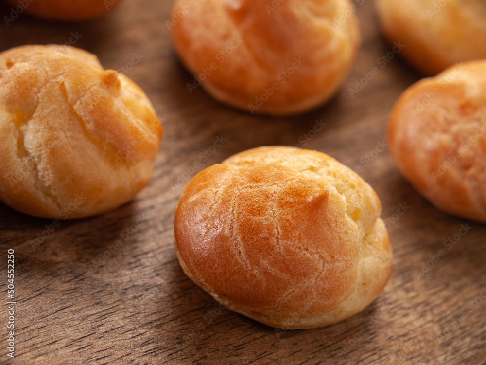 Close up of a homemade profiteroles on a wooden plate. Horizontal. Selective focus.	

