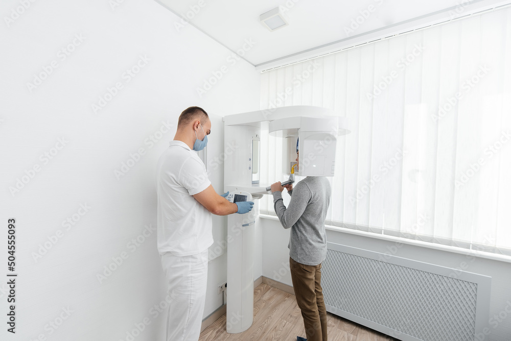 A young man has a computed tomography of the jaw, a circular snapshot of the jaw in modern dentistry. Prevention of caries, prosthetics and dental treatment. Radiology, panoramic scanner. A young man has a computed tomography of the jaw, a circular snapshot of the jaw in modern dentistry. Prevention of caries, prosthetics and dental treatment. Radiology, panoramic scanner.