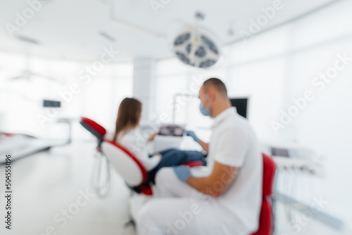 The dentist advises a young beautiful woman about the treatment and prosthetics of teeth in modern white stomatolgia. Dental prosthetics  treatment and teeth whitening.