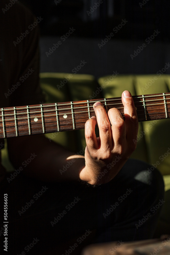 Close up of a male hand on the frets of a guitar in a dark background Close up of a male hand on the frets of a guitar in a dark background