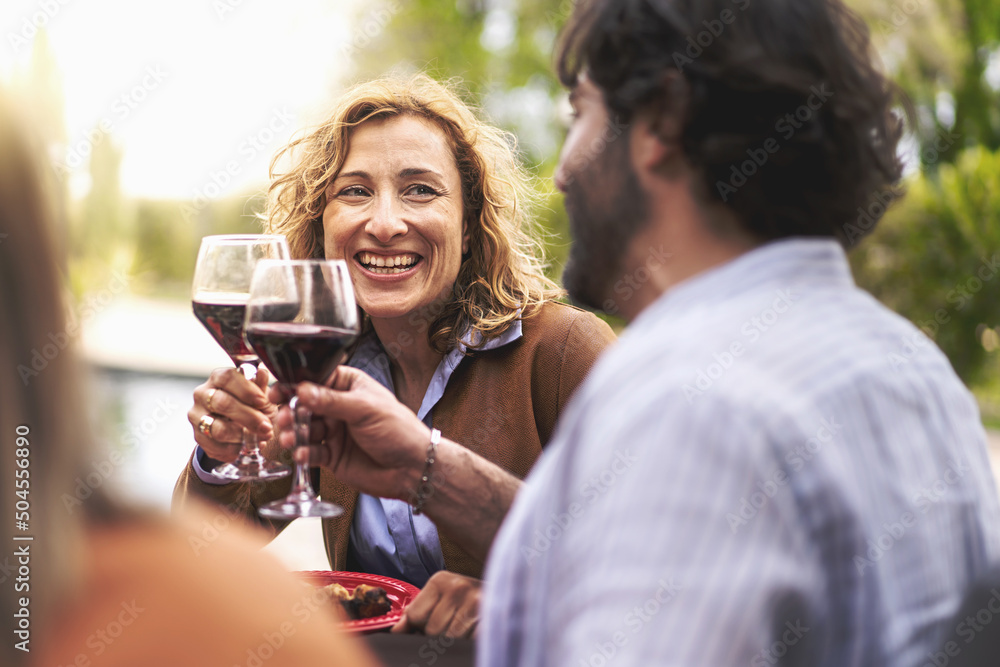 Happy mature couple of 40s people having fun toasting outdoors sitting at the barbecue table - lifestyle conviviality concept - forty-year-olds at the table in a carefree afternoon Happy mature couple of 40s people having fun toasting outdoors sitting at the barbecue table - lifestyle conviviality concept - forty-year-olds at the table in a carefree afternoon