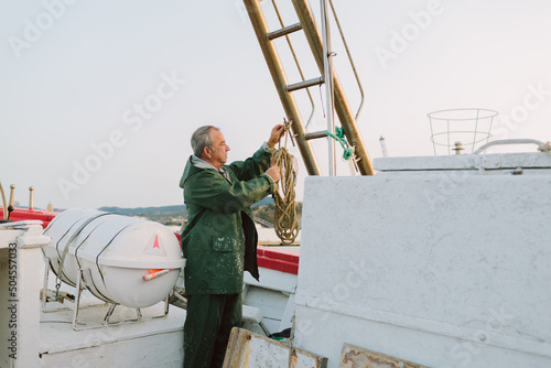 Old fisherman preparing the boat at sunrise