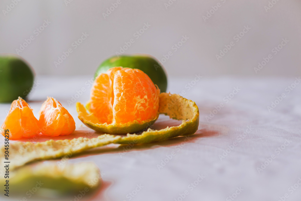 Close-up ,The oranges  on the  table on white backdrop .The oranges have green peel ,peeling orange