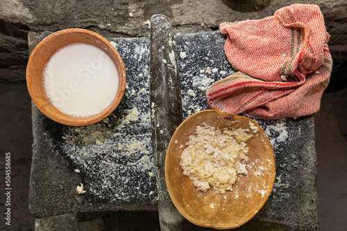 clay bowl with white corn atole next to a jícara with corn dough photo