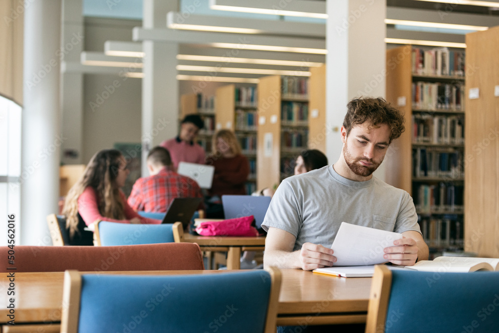 Male Student In Library Reading Assignment Male Student In Library Reading Assignment