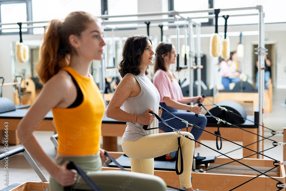 Women's team doing exercises on pilates machine Women's team doing exercises on pilates machine