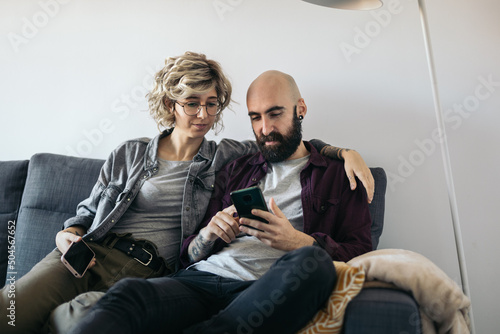 Couple sitting on sofa using mobile photo