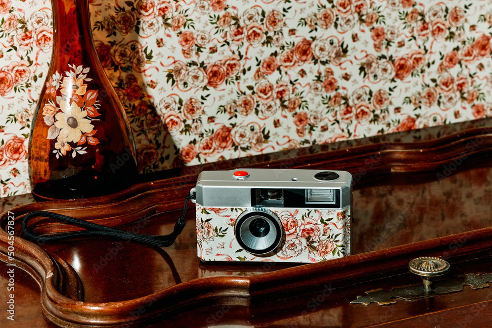 floral camera next to a brown glass vase