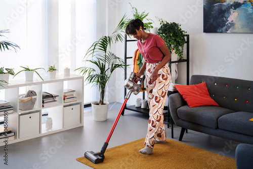 Ethiopian female cleaning floor with vacuum cleaner photo