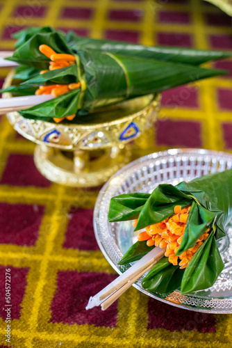 Orange trumpet, candle and incense sticks in banana leaf cones